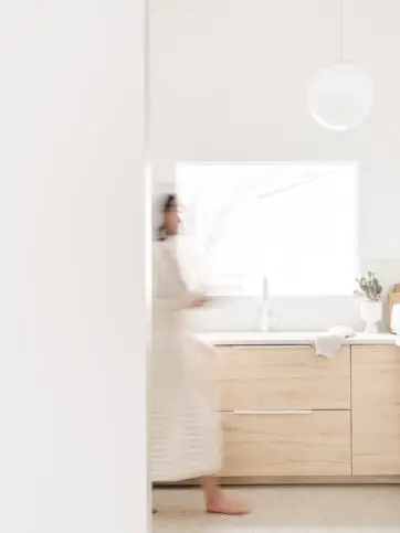 Woman walking through a kitchen during pre-listing home consultations with Pair Home Design.