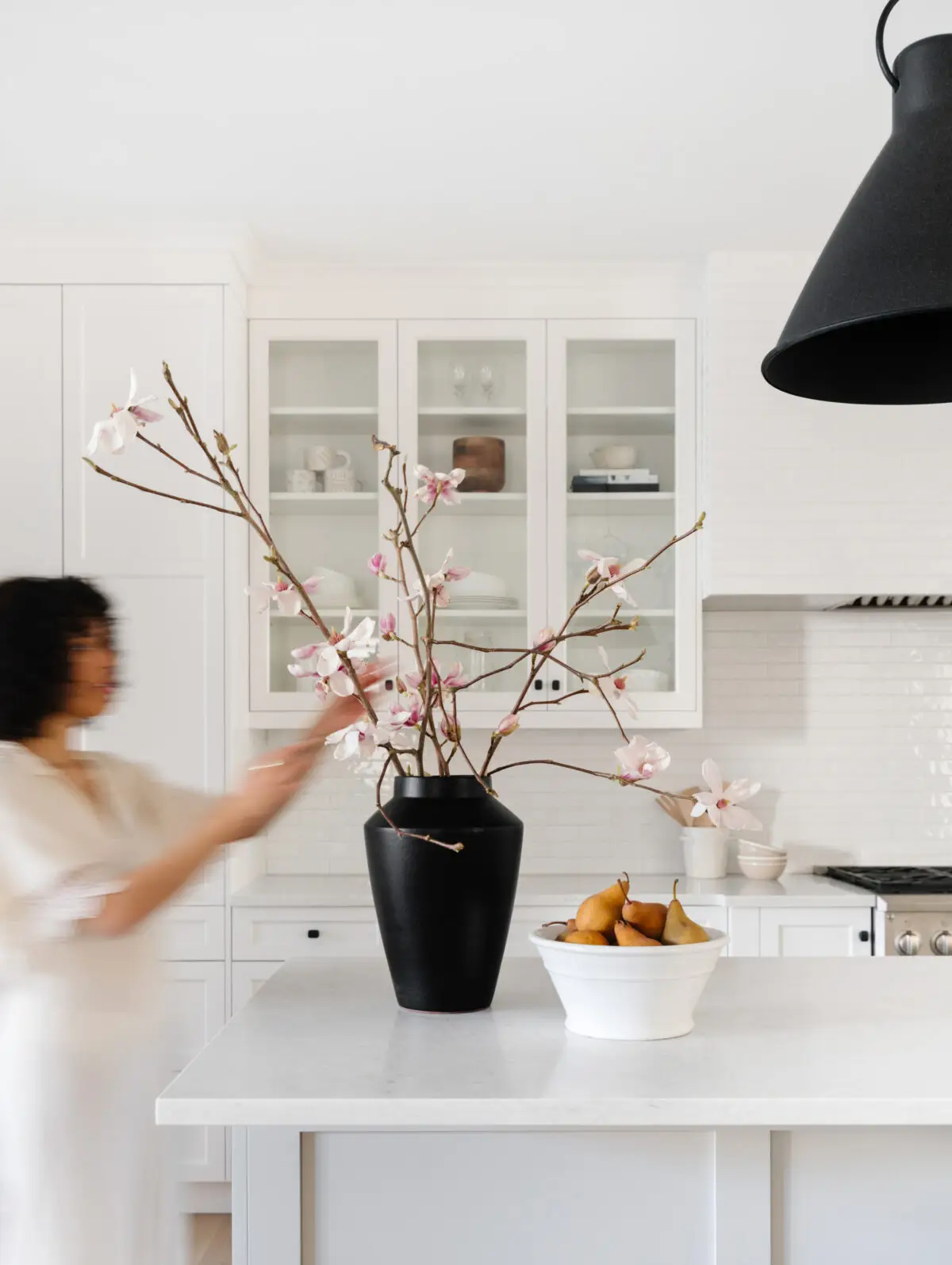 Woman arranging flowers in a kitchen during pre-listing home consultations with Pair Home Design during residential staging services